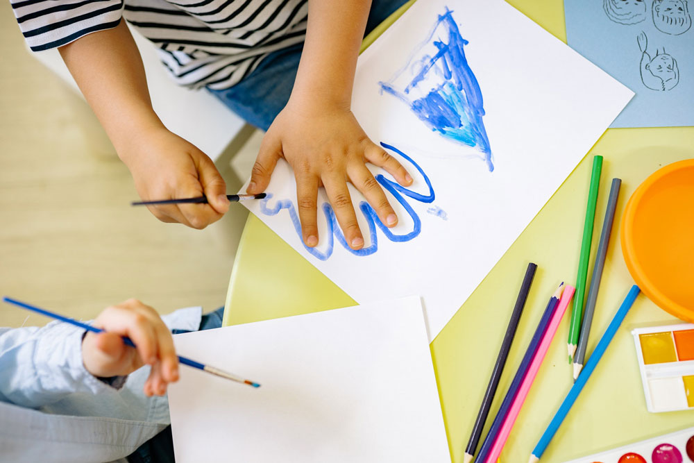 Mano-bambino-scuola-infanzia-con-pastelli-e-colori